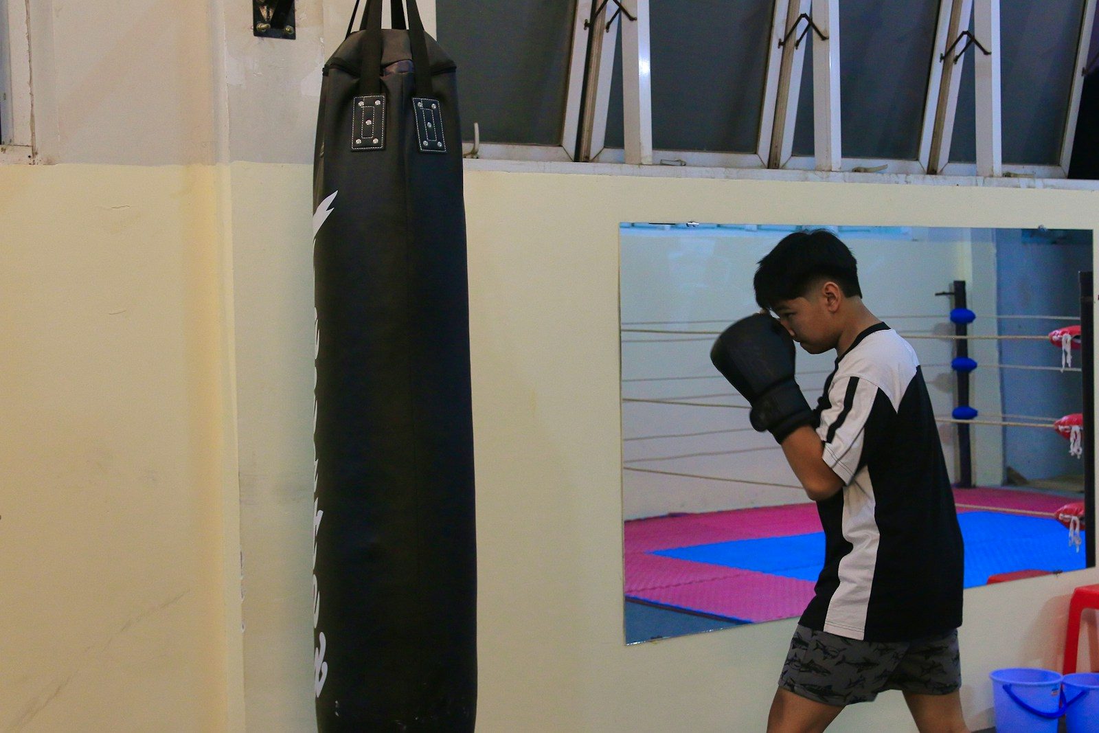 a young man standing next to a punching bag